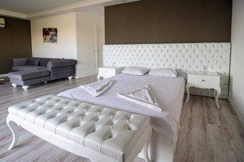 DELUXE VİLLA Kuşadası في كوساداسي: غرفة نوم بيضاء مع سرير كبير وأريكة