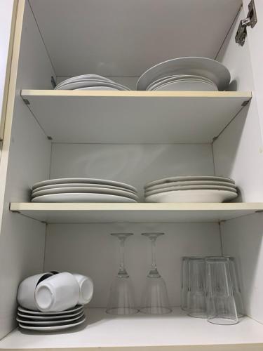 a white cabinet filled with plates and dishes at Apartamento em Maceió in Maceió