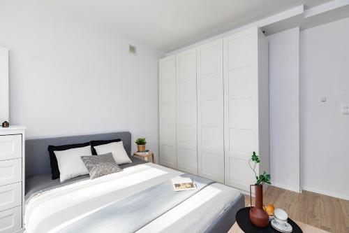 a white bedroom with a large bed with white walls at SuperApart Dzielna 9a in Warsaw
