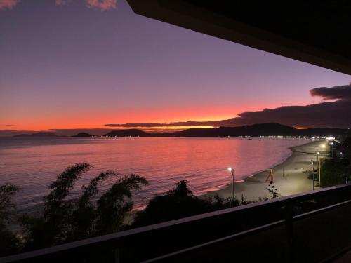 a view of a beach at sunset from a balcony at Cobertura frente ao mar in Florianópolis