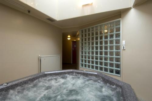 a jacuzzi tub in a room with a window at Ascot Park Hotel in Invercargill