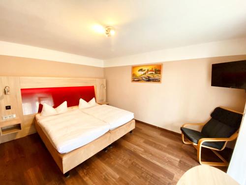 ein Hotelzimmer mit einem großen Bett und einem Stuhl in der Unterkunft Hotel garni Kleindienst in Ursensollen