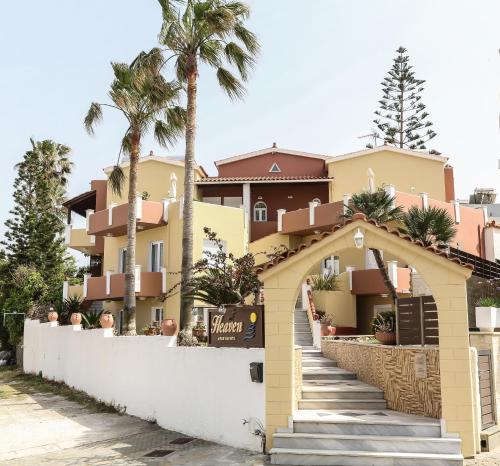 a building with palm trees in front of it at Heaven Apartments in Agia Marina Nea Kydonias