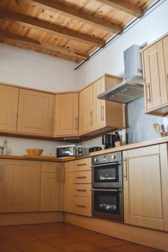 a kitchen with wooden cabinets and a stove at Le Pigeonnier @ Le Prielle in Madiran