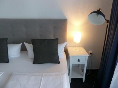 a bedroom with a bed and a nightstand with a lamp at Hotel Lindenufer in Berlin