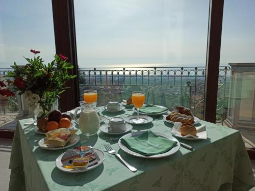 a table with breakfast food and orange juice on a balcony at Hotel Primavera Dell'Etna in Zafferana Etnea
