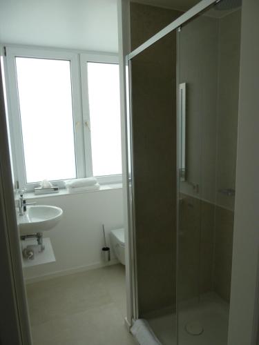 a bathroom with a glass shower and a sink at Hotel Lindenufer in Berlin