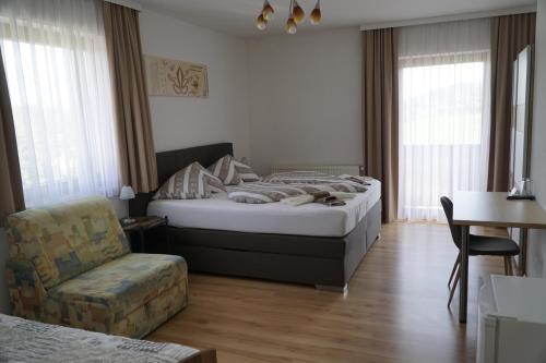 a hotel room with a bed and a chair at Pension-Ferienwohnung Rotar in Faak am See