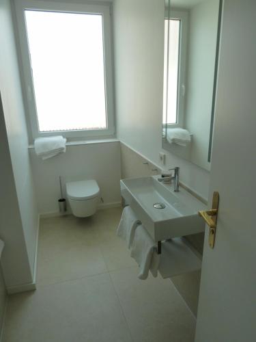 a bathroom with a sink and a toilet and a window at Hotel Lindenufer in Berlin