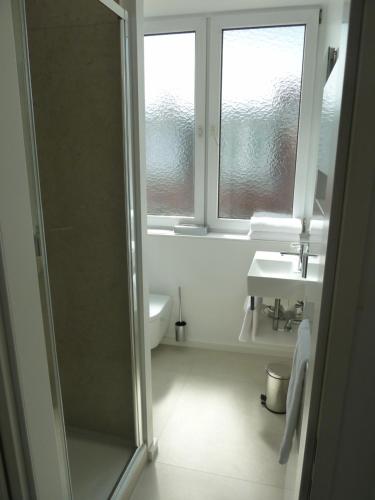 a bathroom with a shower and a sink and a window at Hotel Lindenufer in Berlin