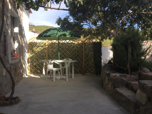 a table and chair under an umbrella in a garden at Kelu e Terra - Locazione Turistica - IUN Q0467 in Onifai