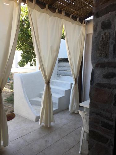 a patio with white curtains and a table and chairs at Kelu e Terra - Locazione Turistica - IUN Q0467 in Onifai