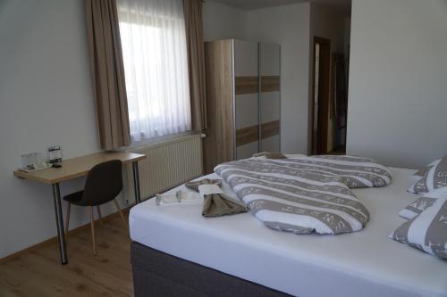 two beds in a room with a table and a desk at Pension-Ferienwohnung Rotar in Faak am See