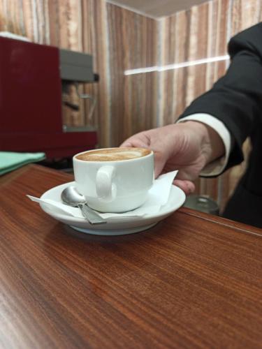 a person holding a cup of coffee on a table at Hotel Primavera Dell'Etna in Zafferana Etnea