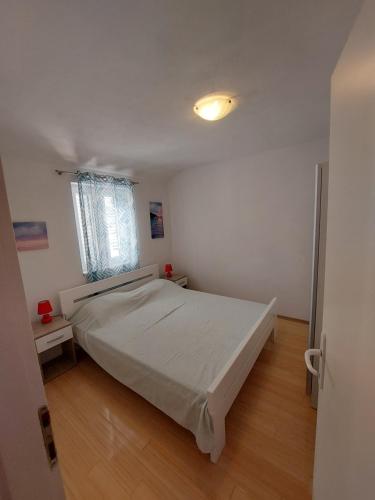 ein Schlafzimmer mit einem großen Bett und einem Fenster in der Unterkunft APARTMAN VERA in Cres