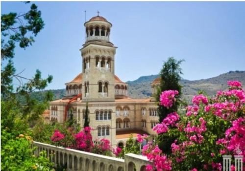 アイギナにあるΆνετο διαμέρισμα στο κέντρο της πόληςのピンクの花が咲いた塔のある大きな建物
