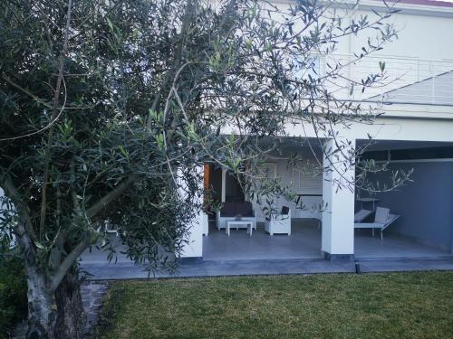 a white house with a patio and a tree at La casa dei Capperi - The house of capers 1 in Acireale