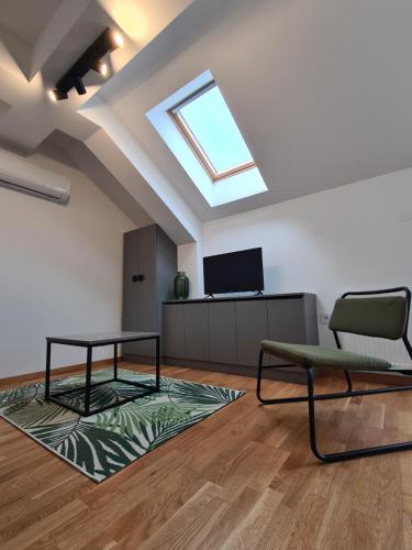 ein Wohnzimmer mit einem Dachfenster sowie einem Tisch und Stühlen in der Unterkunft New Now Living in Novi Sad