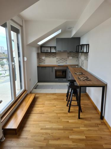 eine Küche mit einem Holztisch und einem großen Fenster in der Unterkunft New Now Living in Novi Sad