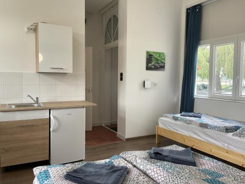 eine Küche mit 2 Betten und einem Waschbecken in einem Zimmer in der Unterkunft Pisztráng17 Apartman in Gárdony
