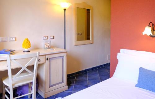 a bedroom with a bed and a desk with a mirror at Hotel Baglio Di Scopello in Scopello
