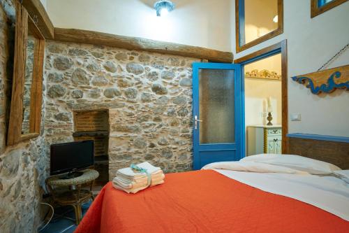 1 dormitorio con cama roja y pared de piedra en Pietra di mare, en SantʼAgata di Militello