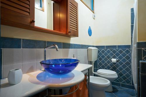 a bathroom with a blue bowl sink and a toilet at Pietra di mare in SantʼAgata di Militello
