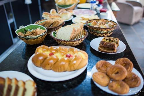 un tavolo sormontato da piatti di pasticcini e pane di Pousada Vale das Orquídeas a Lavrinhas