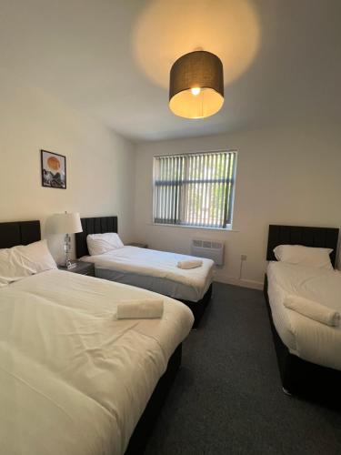 Habitación con 3 camas y luz en The Bake Apartment - 5 bedroom Large Apartment sleeps up to 16 person, en Newcastle