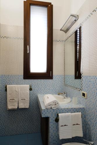 a blue tiled bathroom with a sink and a mirror at Villa Musica in Sannicola