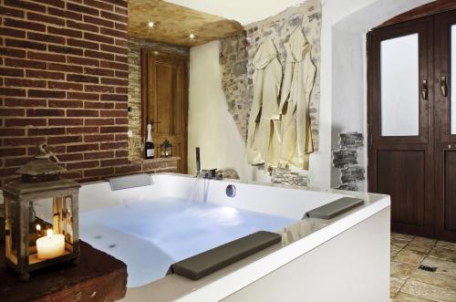 uma grande banheira branca num quarto com uma parede de tijolos em Villa Sofia & Spa em Gaiole in Chianti