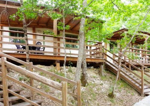 a log cabin with a deck and chairs in the trees at Camping Village la Verna in Chiusi della Verna