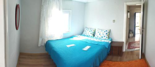 a blue bed in a room with a window at Arzu pansiyon in Aybastı