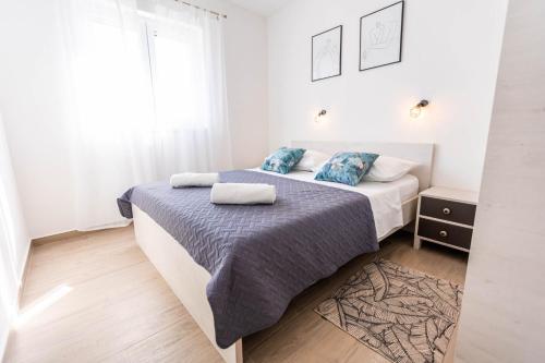 a white bedroom with two beds and a window at Apartments Rising Sun, Ražanac in Ražanac