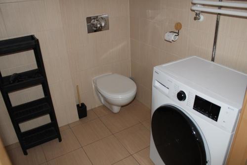 a washing machine in a bathroom with a toilet at Apartament za wydmą Sosnowa 13 in Mielno