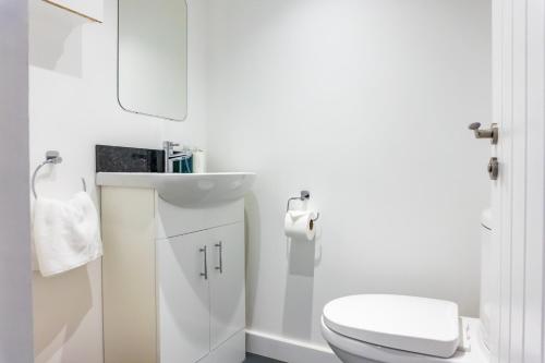 a white bathroom with a toilet and a sink at Inspiration by Olauda SA - 3 Bed House with Free Parking in Swindon