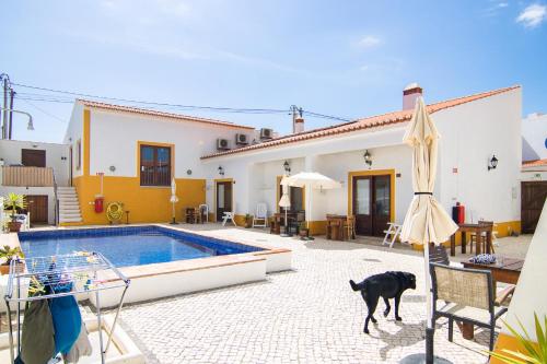a dog walking in front of a house with a pool at Carrapateiramar Guest House in Carrapateira