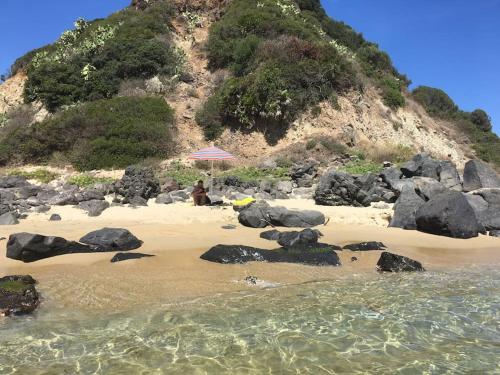 a person sitting under an umbrella on a beach at Kelu e Terra - Locazione Turistica - IUN Q0467 in Onifai