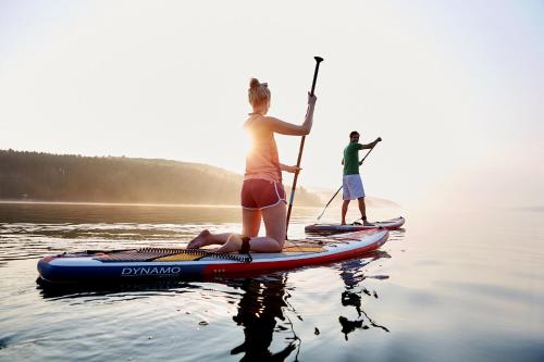 two people are standing on a paddle board on the water at Ferienwohnungen Sonnenseite Brombachsee in Absberg