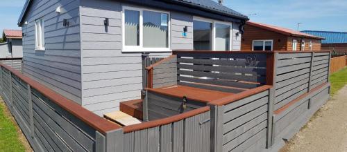 a house with a wooden deck on a fence at luxury 2-Bed modern chalet in Bridlington in Bridlington