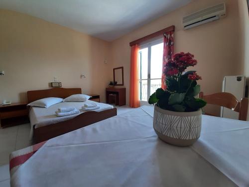 a hotel room with two beds and a vase with flowers at Ammousa Hotel Apartments in Lixouri