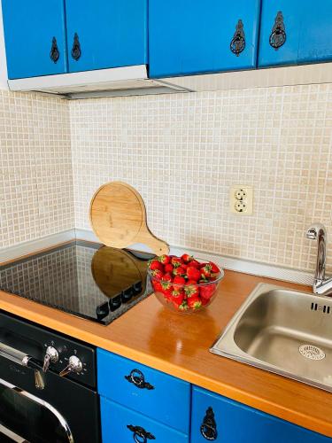 a kitchen counter with a bowl of strawberries next to a sink at Apartment Blue in Sveti Stefan