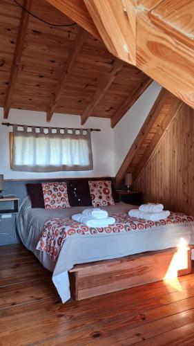 Cama grande en habitación con techo de madera en Posada y Cabañas El Barranco, en El Chaltén