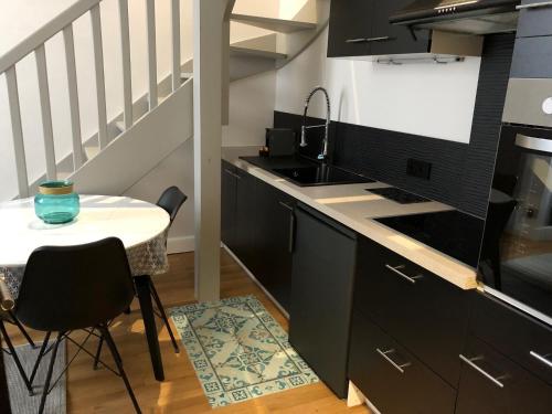 une cuisine avec des armoires noires et une petite table dans l'établissement DUPLEX COSY HYPER CENTRE CHOLET, à Cholet