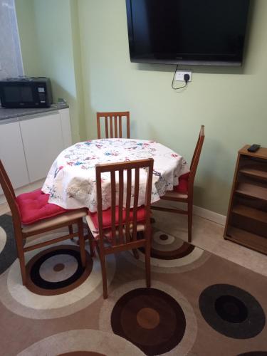 a dining room table with two chairs and a tv at Violet Mays Haven in Starcross