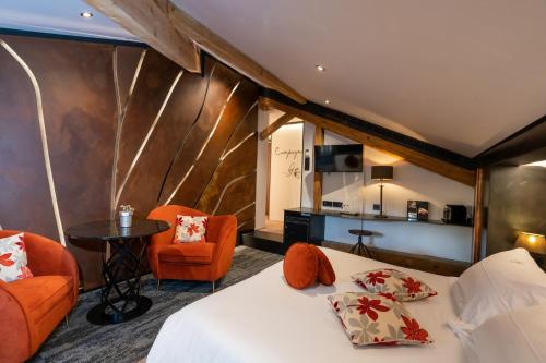 a room with a bed and two chairs and a table at Domaine du Haut Jardin Hôtel & Chalets Spa Privé in Rehaupal