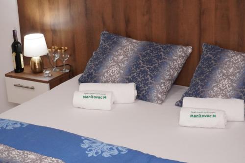 a bedroom with a bed with blue and white pillows at Apartments Manitovac M in Nikšić