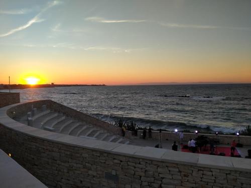 a sunset over the ocean with people standing on the beach at Monolocale prezioso in Trani