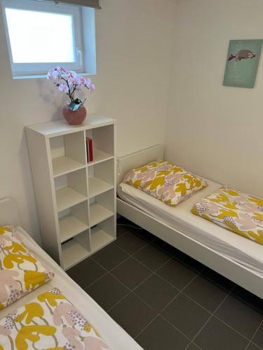 a bedroom with two beds and a shelf with flowers at FeWo Haus 4 in Lahr
