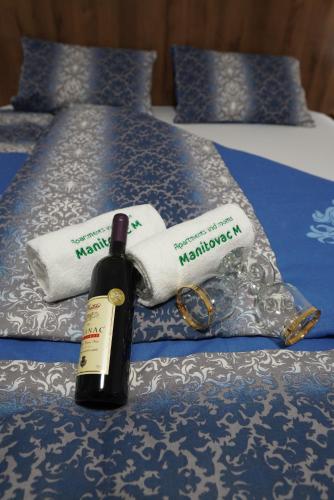 a bottle of wine sitting on top of a bed at Apartments Manitovac M in Nikšić